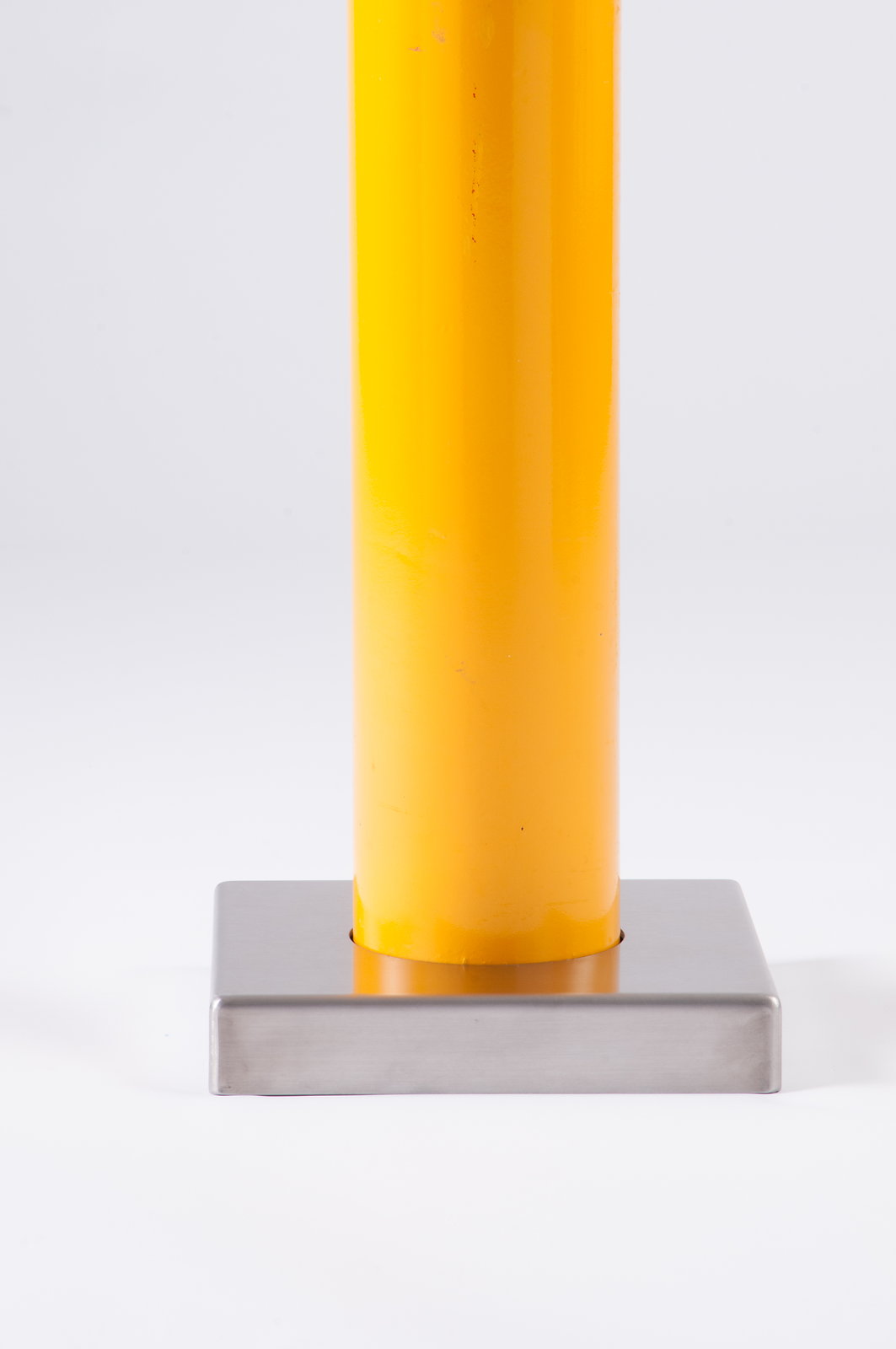 Yellow powder-coated base plate cover concealing bolts on a bolt-down bollard - Park Supplier