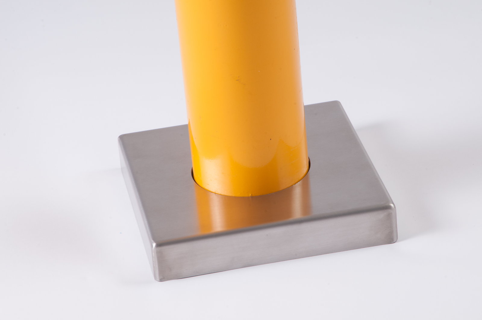 Yellow powder-coated base plate cover concealing bolts on a bolt-down bollard - Park Supplier